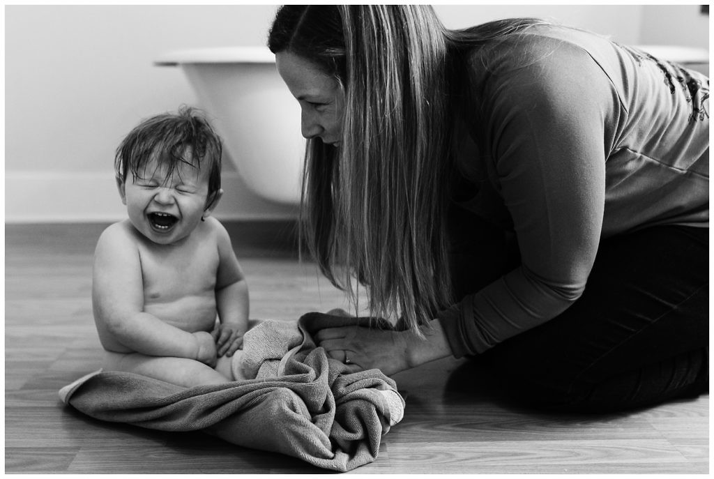 chubby-baby-with-big-laugh-smiles-happily-while-mom-dries-him-with-towel-after-bath