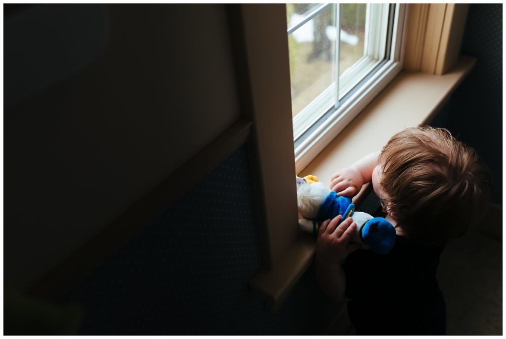 little-boy-holding-his-favourite-stuffed-duck-gazes-out-the-window-at-the-trains-rolling-by
