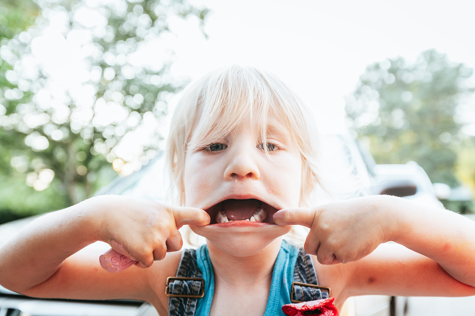 little-girl-holds-mouth-open-and-sticks-out-tongue-on-a-sunny-afternoon-sumer
