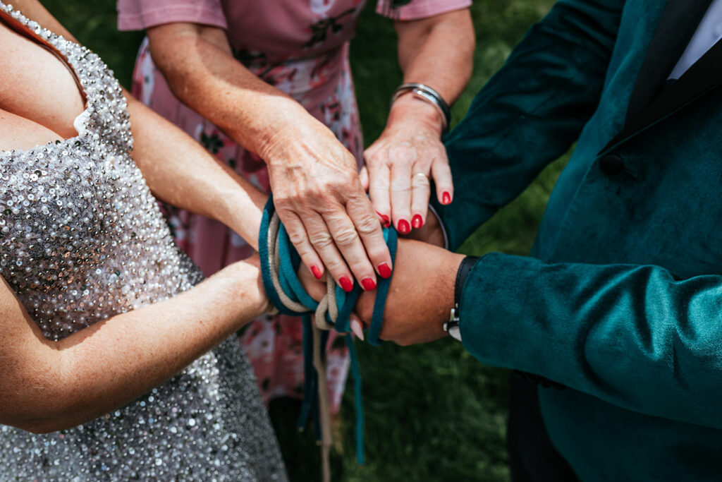 a-couple-has-their-hands-together-and-tied-in-a-traditional-hand-binding-ceremony-in-revelstoke-bc